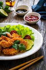 Fried panko prawns with lime, tomatoes and greens wooden table

