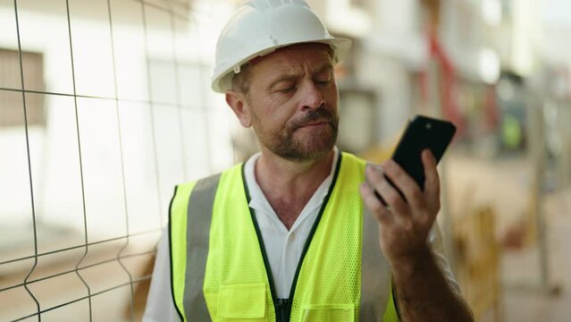 Middle age man architect talking on smartphone with worried expression at street