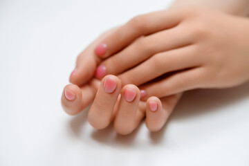 Closeup top view of elegant pastel pink natural manicure. Female hands isolated on white background. Horizontal color photography.