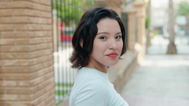 Young hispanic woman smiling confident standing at street