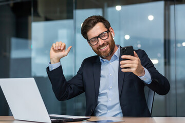 Successful mature businessman in office listening to music and dancing, boss in glasses with phone...
