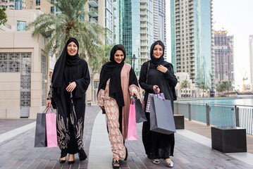 Arabic women wearing traditional middle eastern abaya clothing in Dubai, shopping and having fun...