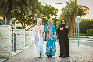 Arabic women wearing traditional middle eastern abaya clothing in Dubai, shopping and having fun outdoors
