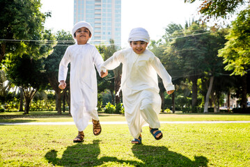 Cute middle eastern kids wearing traditional arab clothing playing and having fun in a park outdoors