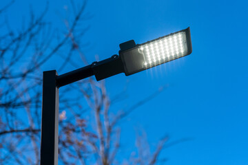 Modern LED city lamp. Street LED lamp. A lit street lamp. - obrazy, fototapety, plakaty