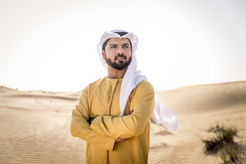 Portrait of handsome middle-eastern man wearing traditional emirates kandora in the desert of Dubai, UAE