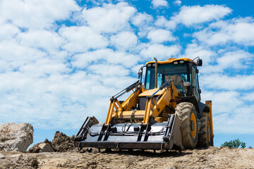 Big yellow excavator. Excavator on the background of the sky with clouds. Excavator at the...
