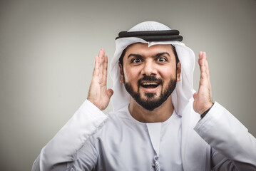 Handsome arab man wearing traditional emirate clothing portrait in studio - Middle eastern businessman isolated on cut-out gray background