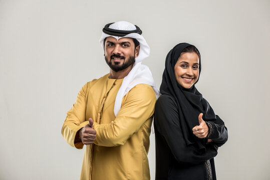 Arabian couple isolated on grey background - Arab man wearing emirates kandora and beautiful muslim woman wearing hijab 