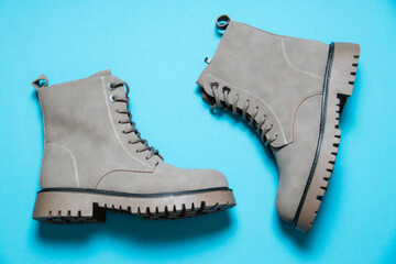 Gray women's winter boots with laces on a blue background. Concept of modern female fashion