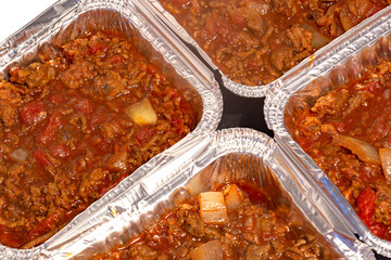 Homemade bolognese sauce filled in individual foil trays ready for freezing. Ideas for cutting the cost of food.