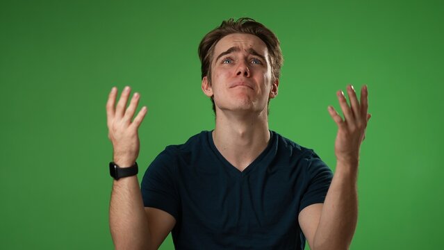 Angry, scared young man 20s put hands on head screaming crying ask why me, isolated on green screen background studio. People lifestyle concept in slow motion