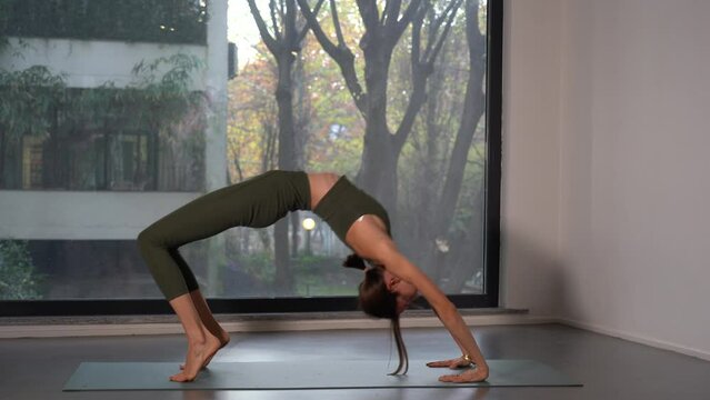 young lady girl performs yoga meditation exercises near the window  - more and more people are dedicating themselves to personal well-being at home or in the gym by doing sports - lifestyle at home 
