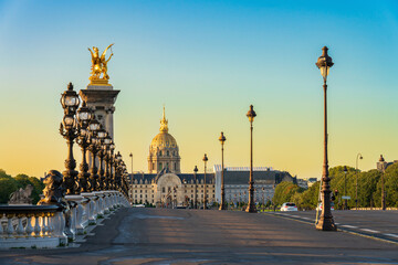 Fototapeta na wymiar Dome of Les Invalides seen across Pont Alexandre III bridge at sunrise in Paris. France