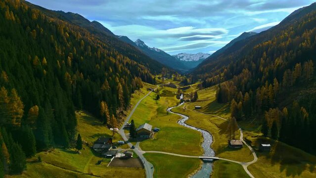 Flight over Davos mountain in autumn with beautiful colored forest and wild river