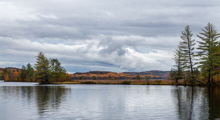 Fototapeta na wymiar looking across the lake to pine trees and fall colour reflection