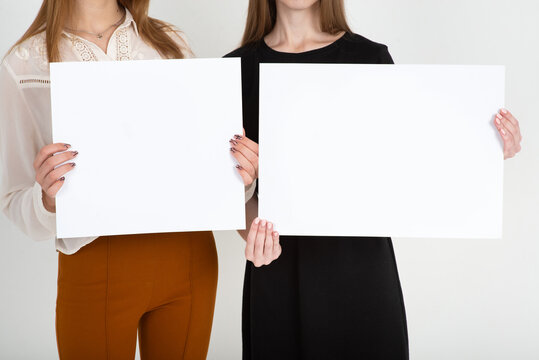 two women holding a white blank sign in their hands