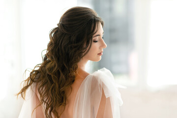 Fototapeta na wymiar Woman in a white wedding dress, with a beautiful hairstyle, back portrait