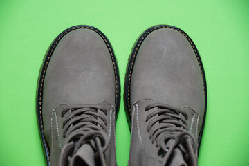 Gray women's winter boots with laces on a green background. Concept of modern female fashion