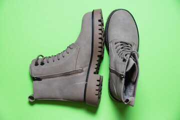Gray women's winter boots with laces on a green background. Concept of modern female fashion