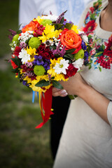 Wedding multi-colored bright bouquet in the hands of the bride in the hands on the street in a wedding dress with Ukrainian embroidery