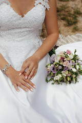 Bride in a stylish white wedding dress. Nearby lies a stylish bouquet of colorful flowers. Image for your creativity, design or illustrations.