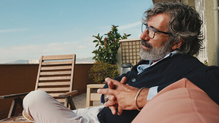 Middle-aged man enjoying sunny weather on the balcony