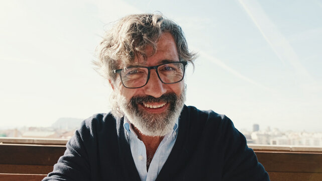 Close-up of mature man taking selfie while standing on balcony, looks at camera