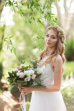 Beautiful bride in a white wedding dress and a bouquet, waist-length