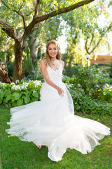 Obraz na płótnie Canvas Beautiful smiling bride in a white wedding dress in the garden