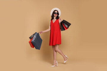 Beautiful young woman with paper shopping bags on beige background