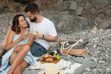 Happy young couple having picnic on beach. Space for text