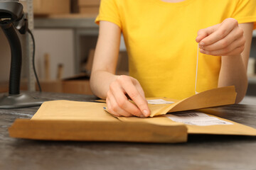 Post office worker with envelopes at counter indoors, closeup