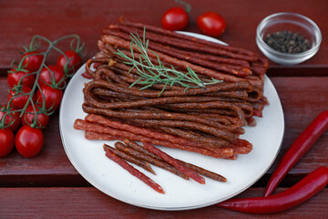 Tasty dry cured sausages (kabanosy) and ingredients on wooden table, above view