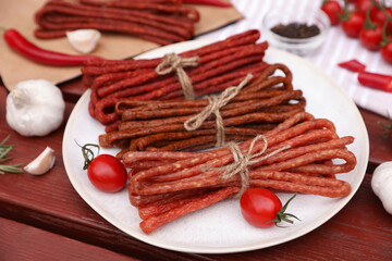Bundles of delicious kabanosy with tomatoes on wooden table