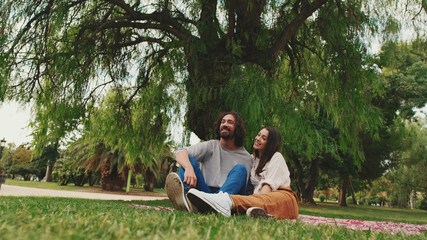 Happy smiling couple talking while sitting on blanket in park