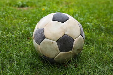 Dirty soccer ball on fresh green grass outdoors, closeup