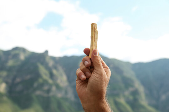 Man holding palo santo stick in high mountains, closeup