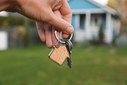 Woman holding house keys outdoors, closeup. Real estate agent