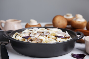 Delicious pasta with mushrooms in pan on table, closeup