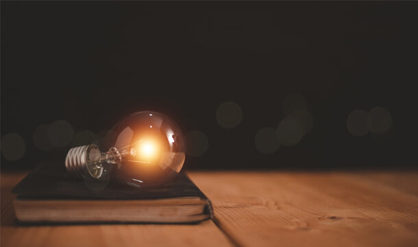 Glowing light bulb on a cover of book, Educational knowledge and business education ideas, Innovations, Inspiring from read concept, knowledge and searching for new ideas. Thinking for new idea.