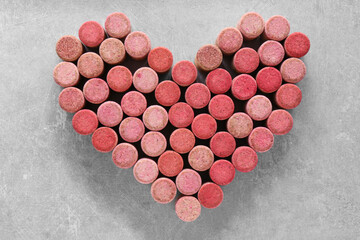 Heart made of wine bottle corks on grey table, top view