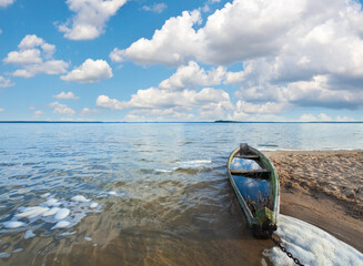 Old flooding boat on summer lake shore