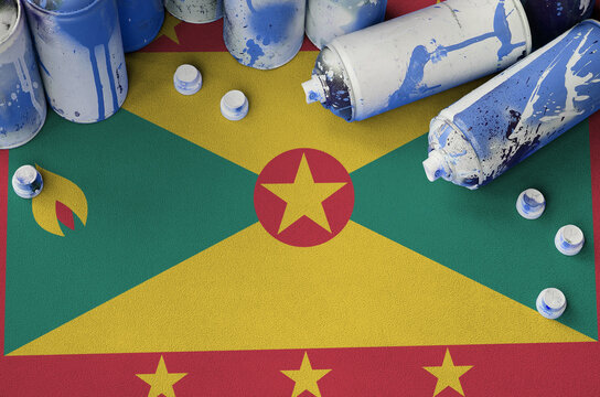 Grenada Flag And Few Used Aerosol Spray Cans For Graffiti Painting. Street Art Culture Concept, Vandalism Problems