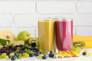 Fresh colorful fruit smoothies and ingredients on white table
