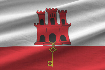 Giblartar flag with big folds waving close up under the studio light indoors. The official symbols...