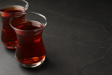 Glasses with traditional Turkish tea on black table, closeup. Space for text
