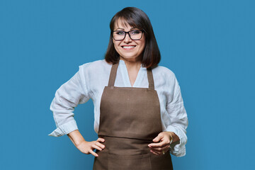 Confident middle aged woman in apron looking at camera on white background