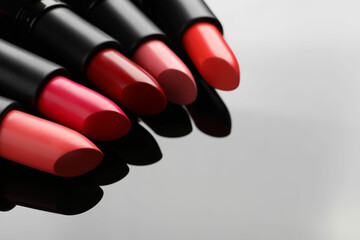 Many bright lipsticks on light grey background, space for text
