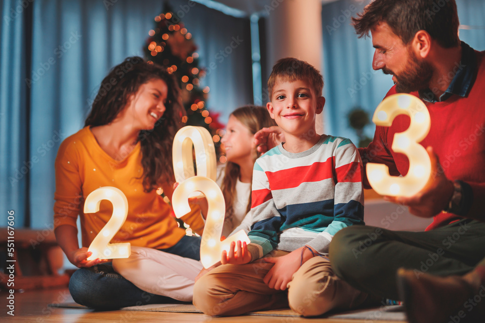 Wall mural parents and children holding illuminative numbers 2023 while celebrating new year